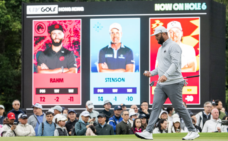 Jon Rahm schreitet mit Golfschläger und Golfball über das Green