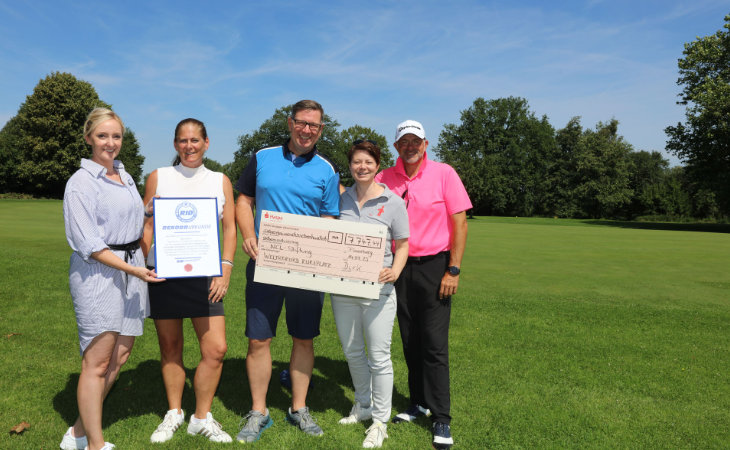 Mehrere Golfer mit einem großen Scheck auf dem Golfplatz