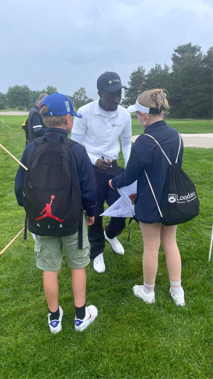 Golfer Ronald Rugumayo gibt zwei Kindern Autogramme