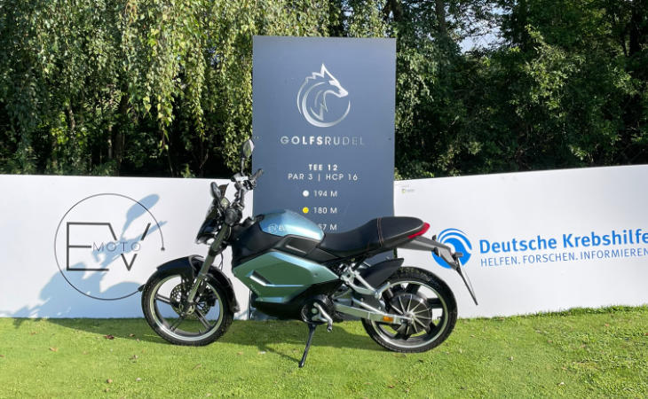 Ein E-Motorrad als Hauptgewinn vor einer Tafel des Golfrudels