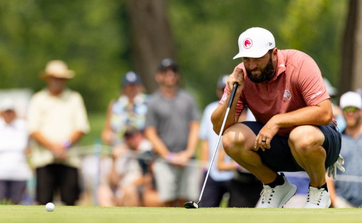 Jon Rahm hockt auf dem Green und visiert seinen Ball an