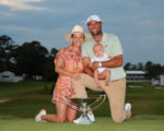 Scottie Scheffler präsentiert den FedExCup mit seiner Frau und seinem Kind.